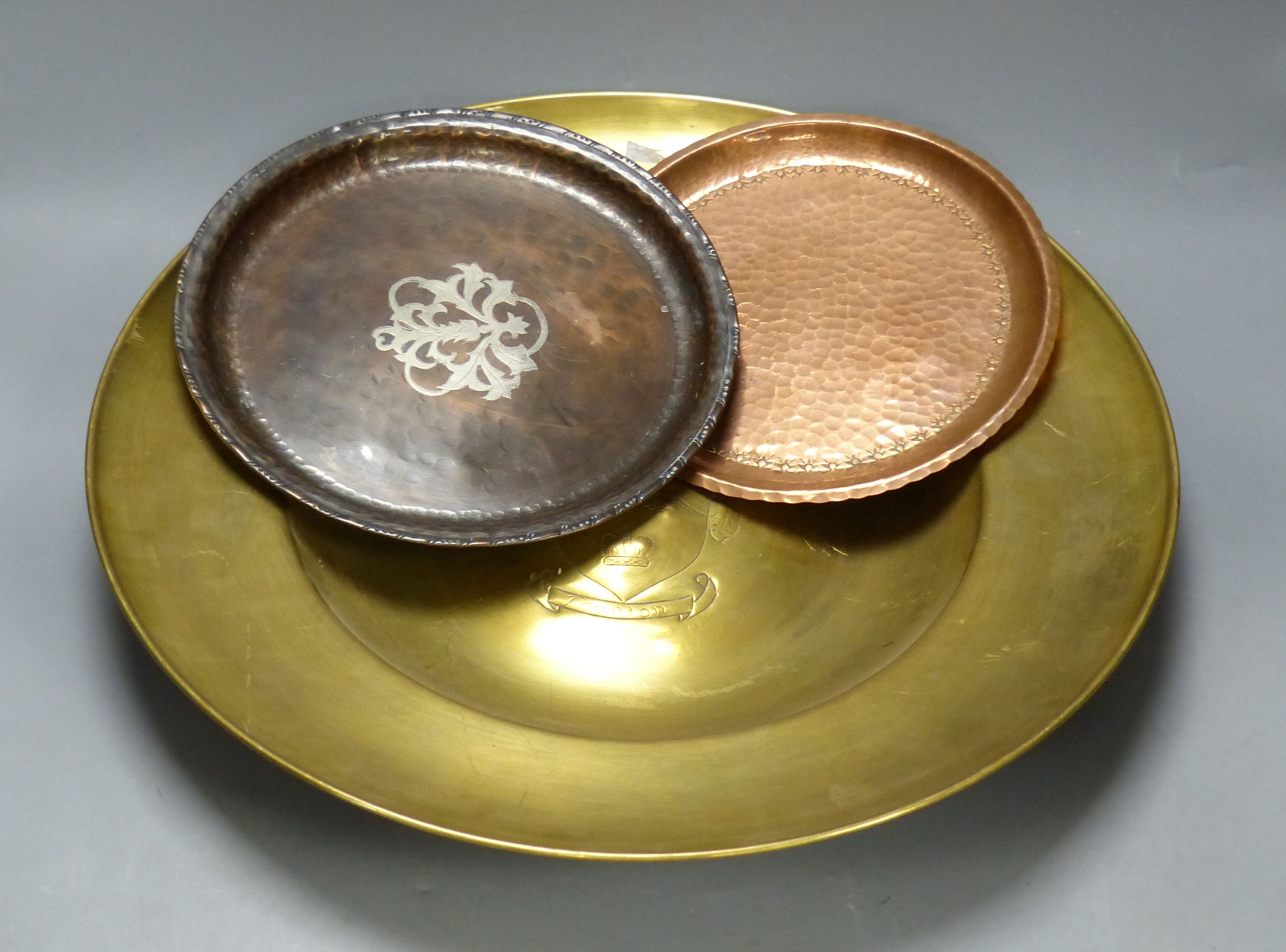 A Hugh Wallace hammered copper dish, a Taunton brass alms dish and another hammered copper dish, diameter 46cm